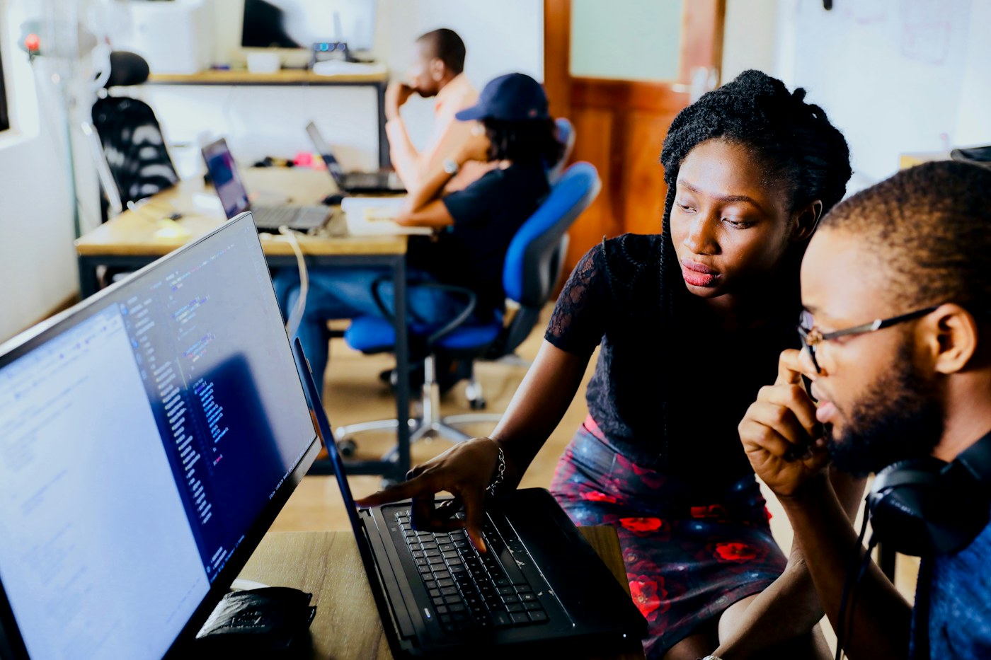 Students collaborating around a laptop in a coding lab